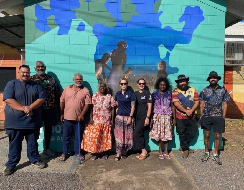 A gruop of people stand in front of a painted wall