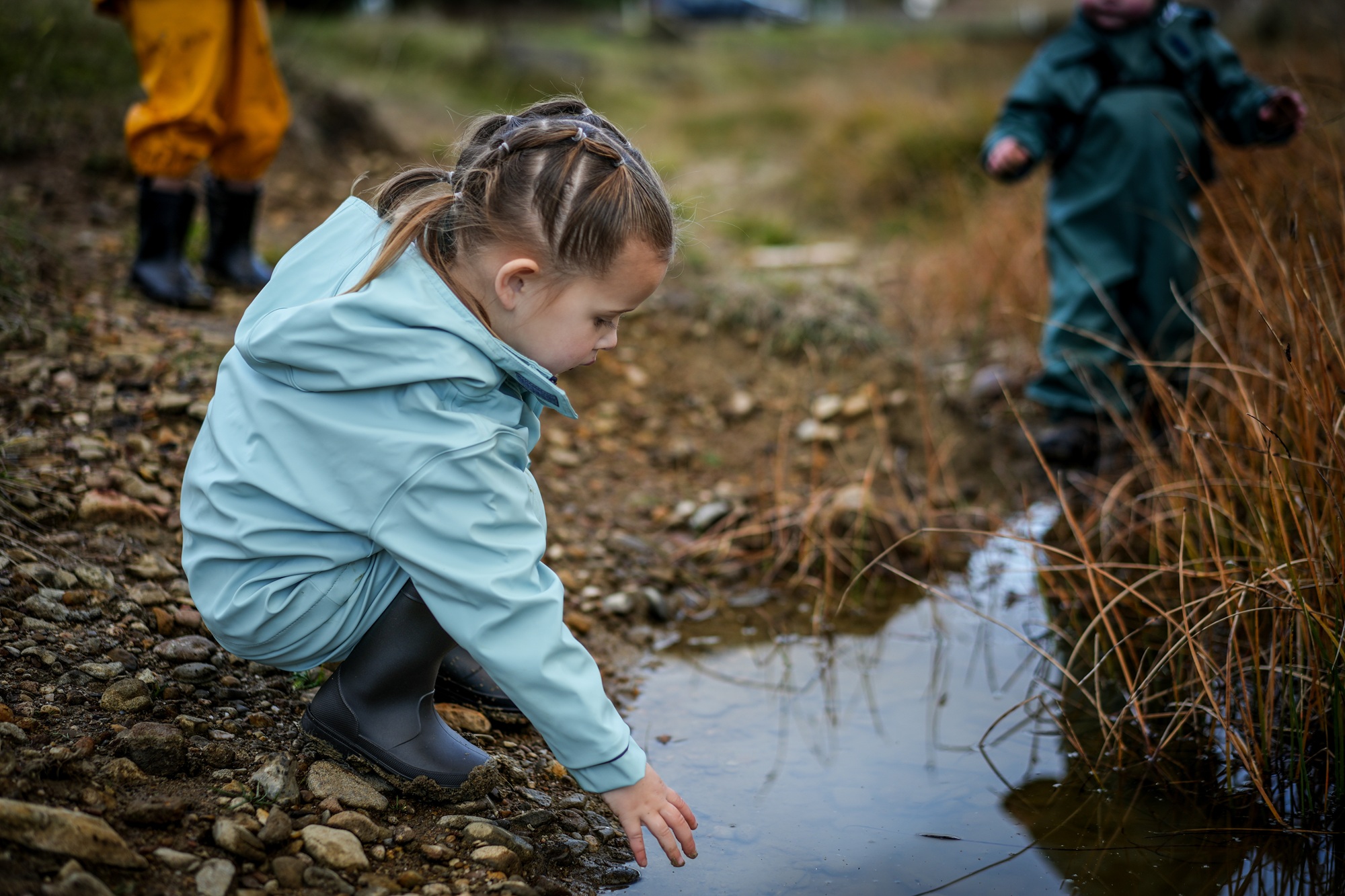 A child puts her hand into a puddle