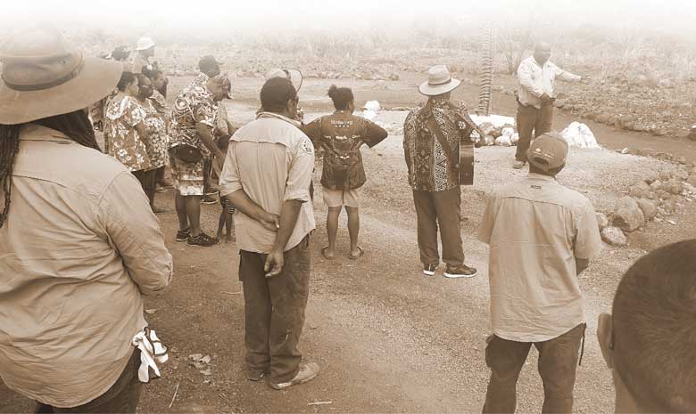 Torres Strait Island rangers and the community standing together celebrating the preservation a 7,200 year old village site